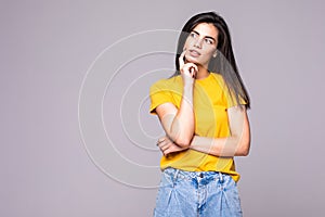 Young cute woman thinking about something on the gray background