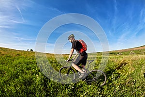 Young cyclist riding mountain bicyclist against beautiful sunrise in the countryside.