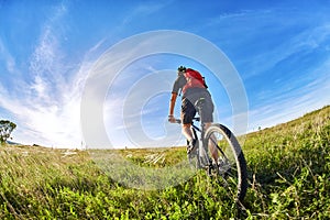 Young cyclist riding mountain bicyclist against beautiful sunrise in the countryside.