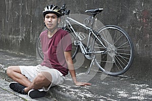 Young Cyclist Sitting At The Roadside