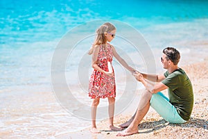 Young dad applying sun cream to daughter nose on the beach. Sun protection