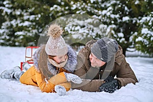 Young dad and his little cute daughter are having fun outdoor in snowy winter