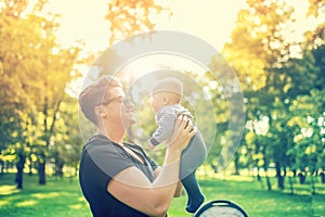 Young dad holding delicate newborn infant in arms outdoor in park. Happy parenting concept, fathers day and family
