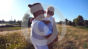 Young dad holding his child on hands at the meadow and stroking him on a sunny day. Father comforting his little son at