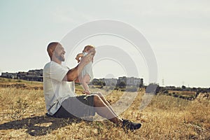 Young dad holds a newborn baby on his outstretched arms. happy father is wearing shorts and a t-shirt. International Father`s Day