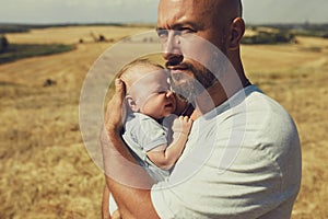 Young dad holds a newborn baby while walking in nature. happy father is wearing shorts and a t-shirt. International Father`s Day