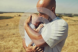 Young dad holds a newborn baby while walking in nature. happy father is wearing shorts and a t-shirt. International Father`s Day