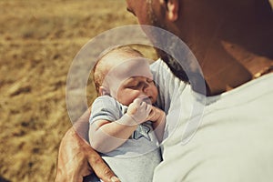 Young dad holds a newborn baby while walking in nature. happy father is wearing shorts and a t-shirt. International Father`s Day