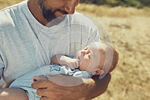 Young dad holds a newborn baby while walking in nature. happy father is wearing shorts and a t-shirt. International Father`s Day