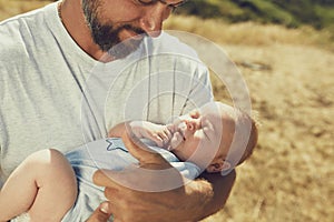 Young dad holds a newborn baby while walking in nature. happy father is wearing shorts and a t-shirt. International Father`s Day