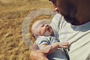 Young dad holds a newborn baby while walking in nature. happy father is wearing shorts and a t-shirt. International Father`s Day