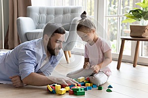 Young daddy and cute little daughter build together with blocks