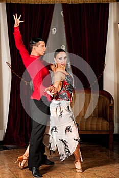 Young dance couple preforming latin show dance in ancient ballroom