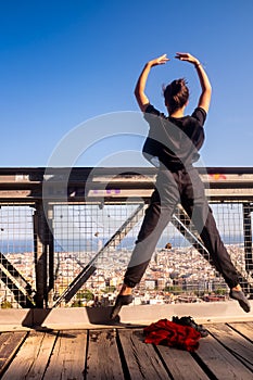 Young dancer jumping in mid-air on the bridge, urban landscape in the background