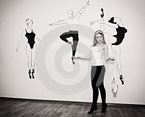 young dancer standing on her toes in a ballet stance with Pointe shoes in hand