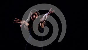 Young dancer woman is performing contemporary dance in dark studio, moving energetic and passionately