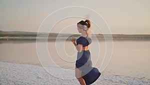 Young dancing girl by the lake in sunset