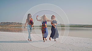 Young dancing girls by the lake in sunset