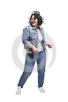 Young dancing plump girl. Beautiful curly brunette with red lips in jeans. Body positivity and freedom. Isolated on white