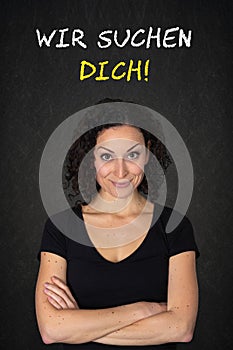 Young smiling woman with crossed arms and the text: `Wie suchen dich`. Translation: `We`re looking for you` photo