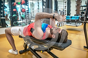 Young dark-haired man working on his body in gym
