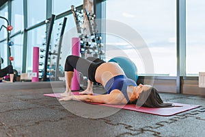 Young dark-haired pregnant woman in sportswear exercising yoga or sports on rug in gym. Health care pregnancy concept