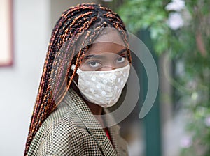 Young dark-skinned girl wearing protective fabric face mask in coronavirus pandemic, COVID-19.