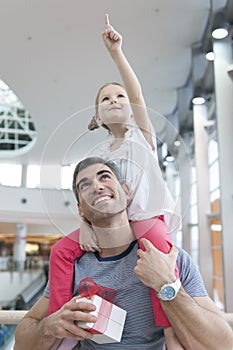 Young daughter points and sits on fathers shoulders