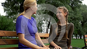 Young daughter sharing secrets with mom, relaxing in park, trusting relationship photo