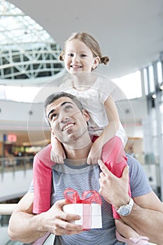 Young daughter sits on fathers shoulders