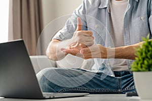 Young deaf man using laptop computer for online video conference call learning and communicating in sign language