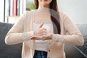 A young deaf woman is sitting on a couch and making a sign Language to communicate