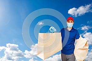 Young Delivery Man Carrying Cardboard Box In Front Of sky background