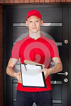Young delivery man with clipboard and package