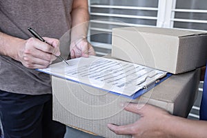 Young Delivery man deliver box parcel package and sending to customer in front of the house, Man customer signing in clipboard
