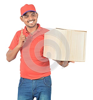 Young delivery man holding carton box and pointing finger in uni