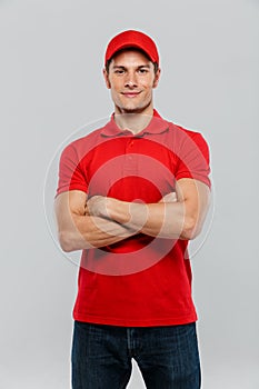 Young delivery man smiling while posing with arms crossed