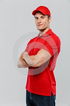 Young delivery man smiling while posing with arms crossed