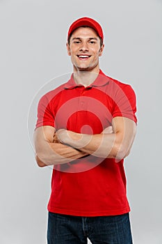 Young delivery man smiling while posing with arms crossed