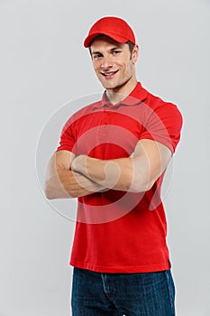 Young delivery man smiling while posing with arms crossed
