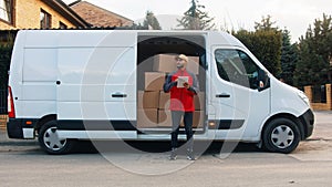 Young delivery man using tablet to find the address and deliver parcel