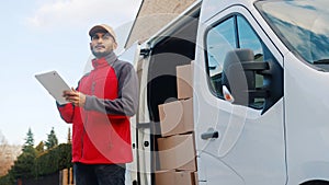 Young delivery man using tablet to find the address and deliver parcel photo