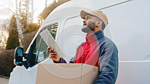 Young delivery man using tablet to find the address and deliver parcel