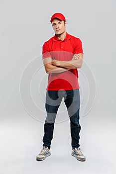 Young delivery man wearing uniform posing with arms crossed