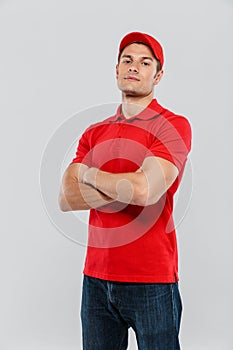 Young delivery man wearing uniform posing with arms crossed