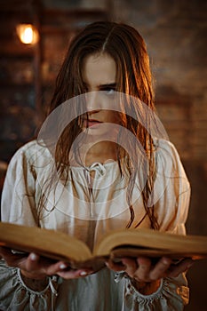 Young demonic woman holds book of spells