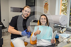 Young dentist doctor and female patient showing thumbs up.