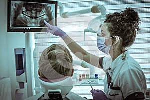 Young dentist examining medical X-ray with patient.