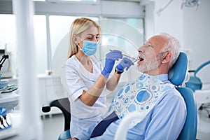 Young dentist examining teeth of an elderly patient