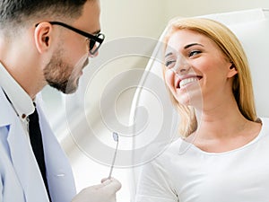 Young dentist talks with patient in dental clinic.